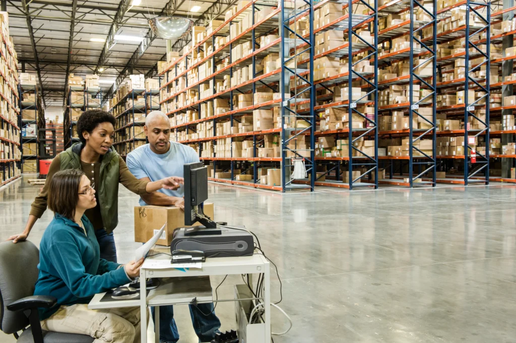 Warehouse workers looking at warehouse management system on computer