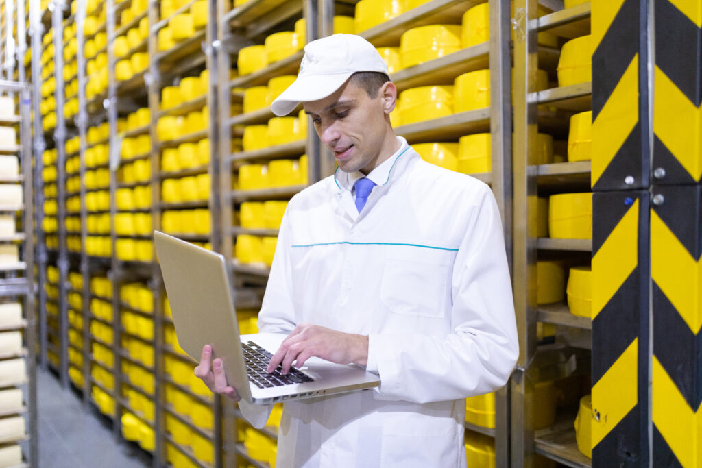 worker with a laptop in his hands at the cheese warehouse